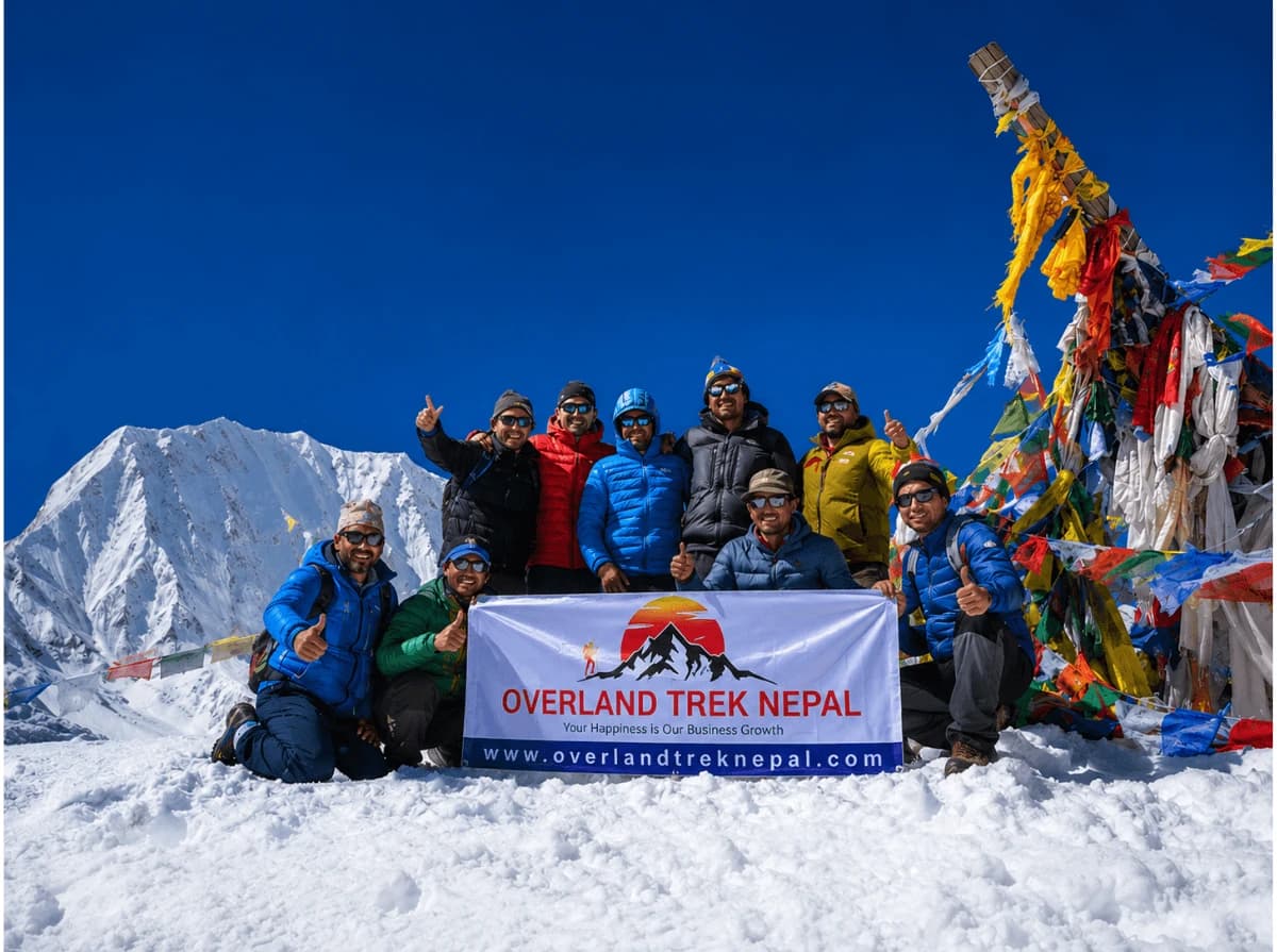 Trekkers with the Overland Trek Nepal banner at Larkya La Pass (5,106m) during the 14 Days Manaslu Circuit Trek in Nepal.